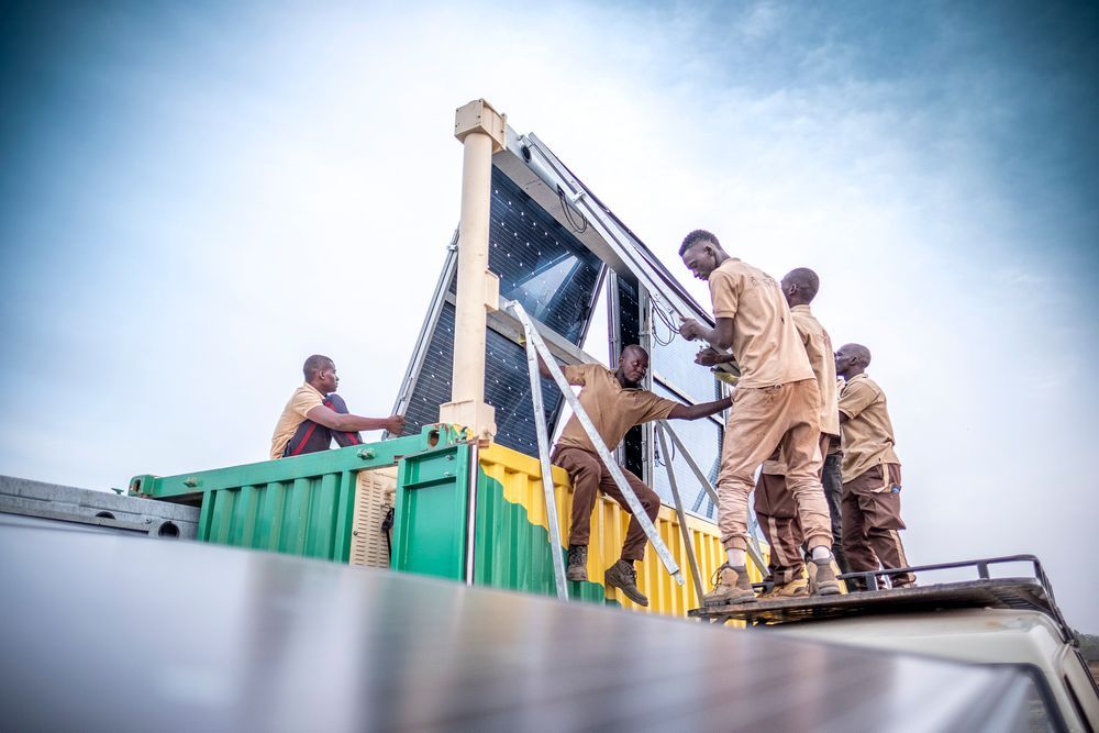 Afrikanische Handwerker errichten einen Solarkollektor auf einem Dach