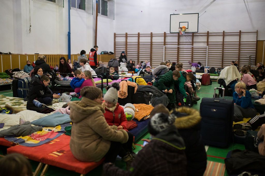 Dicht gedrängt sitzen Geflüchtete auf Notbetten in einer Turnhalle