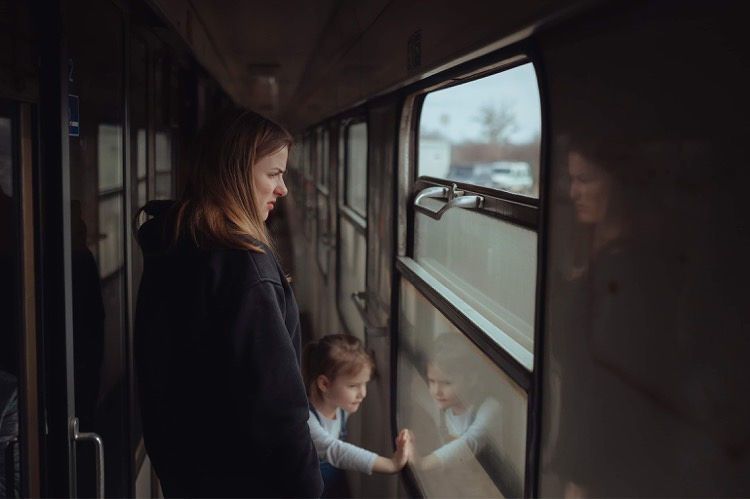 Junge Ukrainerin mit kleiner Tochter - beide schauen aus dem Zugfenster
